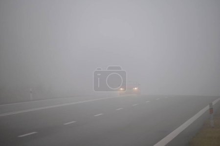 Photo for Cars in the fog. Bad winter weather and dangerous automobile traffic on the road. Light vehicles in fog. - Royalty Free Image