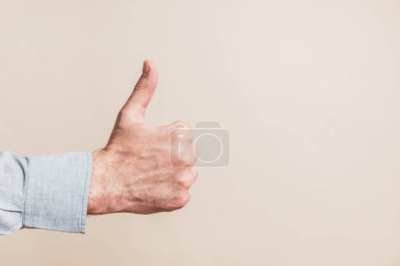 Téléchargez les photos : Male hand showing thumb up on beige background - en image libre de droit