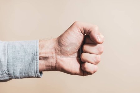 Téléchargez les photos : Image of male fist on beige background - en image libre de droit