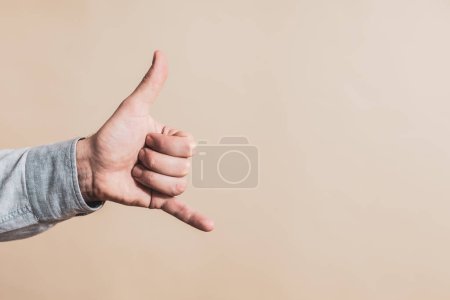 Téléchargez les photos : Main masculine montrant appel moi geste sur fond beige - en image libre de droit