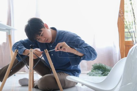 Téléchargez les photos : Jeune homme faisant du bricolage, assemblant des meubles à la maison. - en image libre de droit