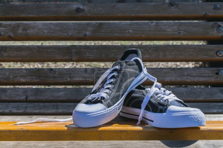 Photo for Pair of sports summer shoes on a park bench - Royalty Free Image