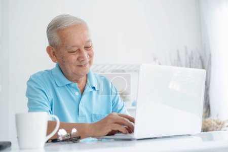Photo for Happy senior man working on laptop and holding coffee cup - Royalty Free Image