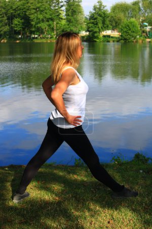 Téléchargez les photos : Femme faisant remise en forme près du lac - en image libre de droit