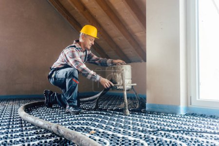 Photo for Worker on construction site installing pipes for underfloor heating - Royalty Free Image