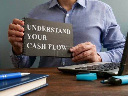 Photo for "Man shows Understand your cash flow sign on page." - Royalty Free Image