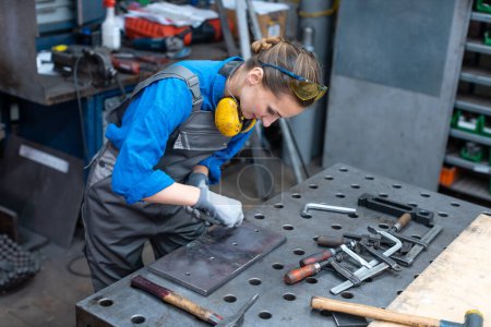 Photo for "Sideview of worker woman marking piece of metal" - Royalty Free Image