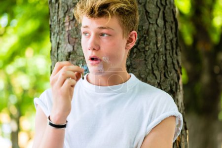 Photo for Young boy smoking in park - Royalty Free Image