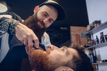 Photo for Head of a man and the hand of a barber trimming his beard - Royalty Free Image