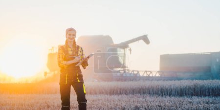 Photo for Farmer woman and combine harvester on wheat field - Royalty Free Image