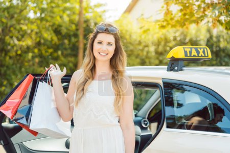 Photo for Woman getting out of Taxi car carrying shopping bags - Royalty Free Image