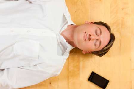 Foto de Hombre acostado en el suelo junto al teléfono móvil - Imagen libre de derechos