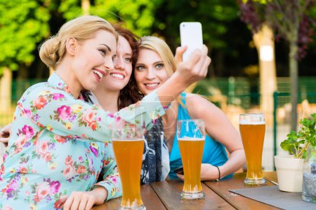 Foto de Amigos tomando selfie con teléfono inteligente en el jardín de cerveza - Imagen libre de derechos