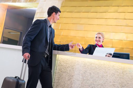 Téléchargez les photos : "Hôtel réceptionniste check in homme donnant carte-clé
" - en image libre de droit