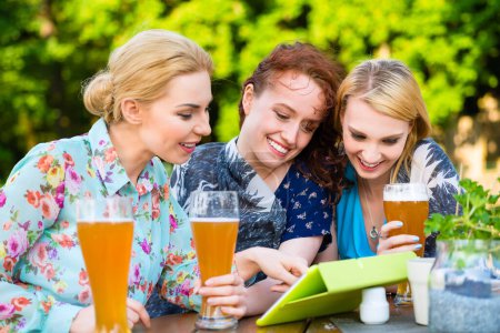 Foto de "Mujer mostrando amigos toque almohadilla en el jardín de cerveza
 " - Imagen libre de derechos