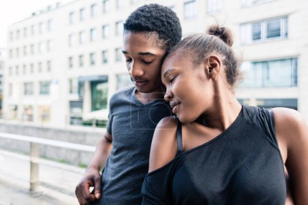 Téléchargez les photos : "Jeune couple afro-américain amoureux debout côte à côte à l'extérieur dans la ville" - en image libre de droit