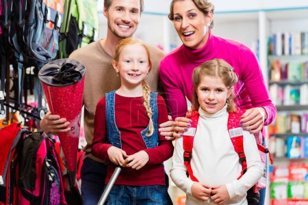 Foto de Familia con dos niños eligiendo la mochila escolar en la tienda - Imagen libre de derechos