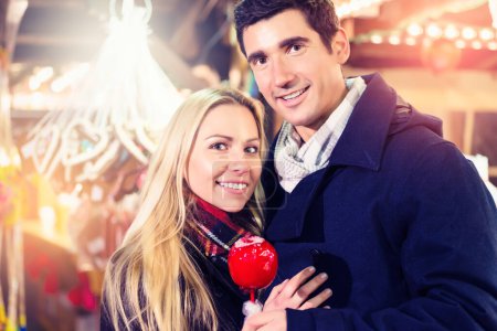 Photo for "Couple with sweet apple on Christmas market" - Royalty Free Image