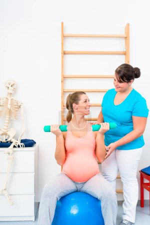 Téléchargez les photos : "Femme enceinte travaillant avec des haltères en physiothérapie
" - en image libre de droit