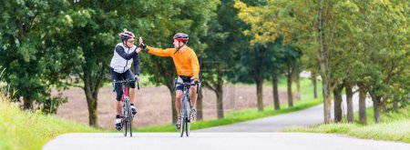 Photo for "Racing cyclists after sport and giving high five" - Royalty Free Image