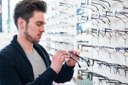 Photo for "Man in front of shelf with glasses in optician shop" - Royalty Free Image