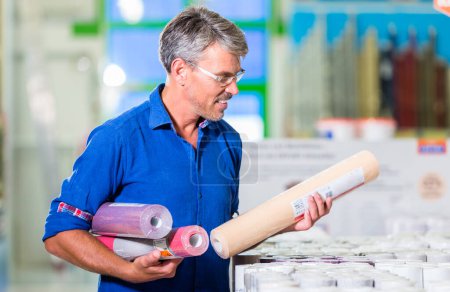 Photo for "Dad choosing wallpapers for girls room in hardware store" - Royalty Free Image