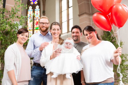 Photo for Family with baby at the altar after the christening, with red balloons - Royalty Free Image