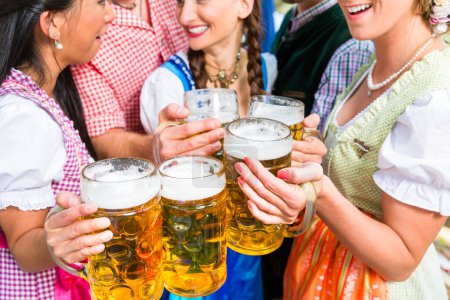 Téléchargez les photos : Amis s'amuser dans le jardin de bière tout en cliquetis lunettes - en image libre de droit