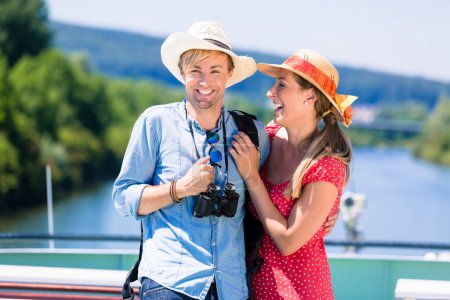 "Happy couple on river cruise in summer wearing sun hats"