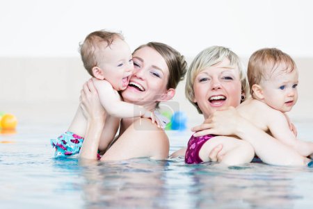 Téléchargez les photos : Les mères et leurs petits enfants s'amusent à la leçon de natation pour bébés - en image libre de droit