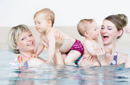 Foto de Las madres y sus hijos pequeños se divierten en la lección de natación del bebé - Imagen libre de derechos