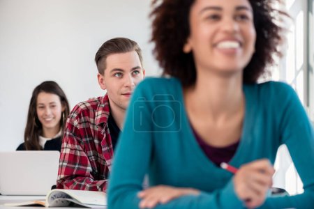 Foto de Estudiante sonriendo mientras usa una tableta durante la clase en una universidad moderna - Imagen libre de derechos