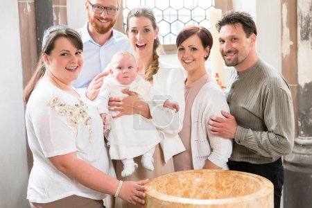 Photo for Family with baby standing around the baptismal font - Royalty Free Image