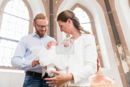 Photo for "Parents with baby at christening in church" - Royalty Free Image