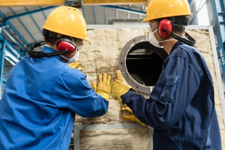 Photo pour "Workers applying insulation material to an industrial boiler" - image libre de droit