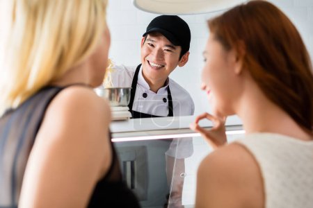 Photo for Smiling young man serving two ladies - Royalty Free Image