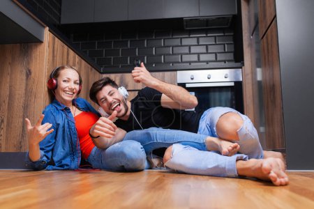 Foto de "pareja engañando arjalá en el suelo de una cocina moderna" - Imagen libre de derechos