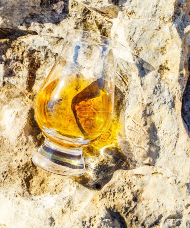 Foto de Whisky de malta simple en vidrio sobre la roca, beber sobre una piedra natural - Imagen libre de derechos