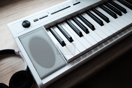 Téléchargez les photos : "clavier de musique blanche avec écouteurs sur table en bois" - en image libre de droit