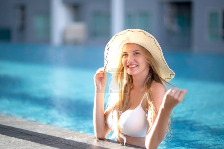 Photo for "woman in white bikini tanning by the pool" - Royalty Free Image