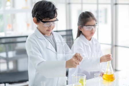 Photo for "Little boy and girl scientist enjoy to examine the color chemical in laboratory by using dropper with day light. Concept of good practice and education of science for children support." - Royalty Free Image