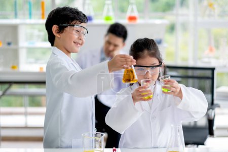 Photo for "Little boy and girl scientist enjoy to examine the color chemical in laboratory by girl compare color of chemical. Concept of good practice and education of science for children support." - Royalty Free Image