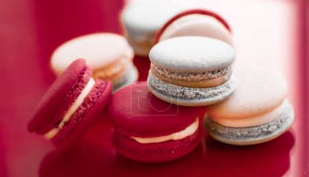 Téléchargez les photos : "French macaroons on wine red background, parisian chic cafe dessert, sweet food and cake macaron for luxury confectionery brand, holiday backdrop design" - en image libre de droit