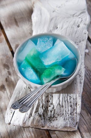 Foto de Cuenco de cubos de hielo de colores en la mesa de madera - Imagen libre de derechos