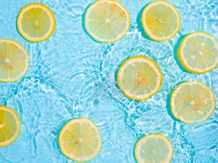 Photo for Lemon slices in clean transparent water, blue background - Royalty Free Image