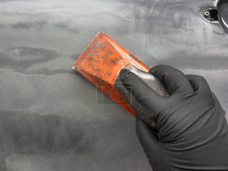 Foto de Procesamiento de masilla con herramientas manuales. tecnología para reparar la pintura de un coche - Imagen libre de derechos