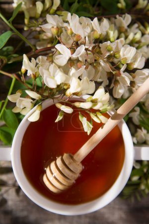 Foto de Primer plano de miel de acacia con cuchara de miel de madera - Imagen libre de derechos