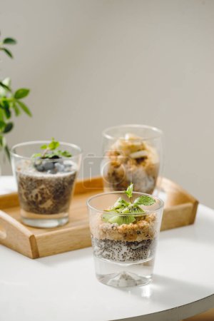 Photo for "Fruits yogurt parfait with granola and chia seeds for healthy breakfast on wooden table" - Royalty Free Image