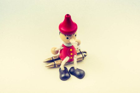 Photo for Bullets and wooden Pinocchio with his long nose - Royalty Free Image
