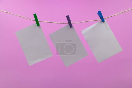 Photo for Empty paper sheets for notes, clothespins pink colored background - Royalty Free Image